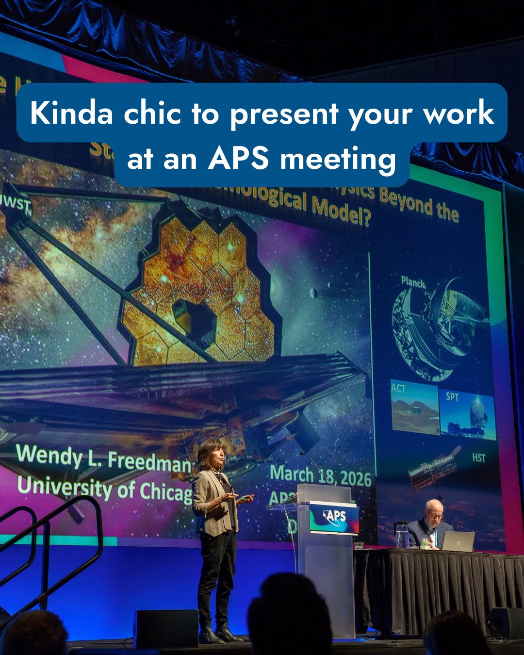 Presentation at an APS meeting. A person stands onstage with a microphone, presenting in front of a large screen displaying images of telescopes, including NASA's JWST and Planck. Another person is seated at a table with a laptop. The slide includes the name Wendy L. Freedman and the University of Chicago, dated March 18, 2026. A text overlay at the top reads, "Kinda chic to present your work at an APS meeting.