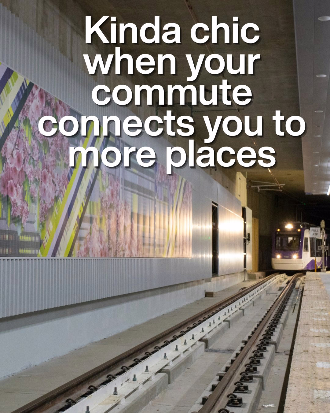 Modern train station platform with floral wall art and a train arriving in the background.