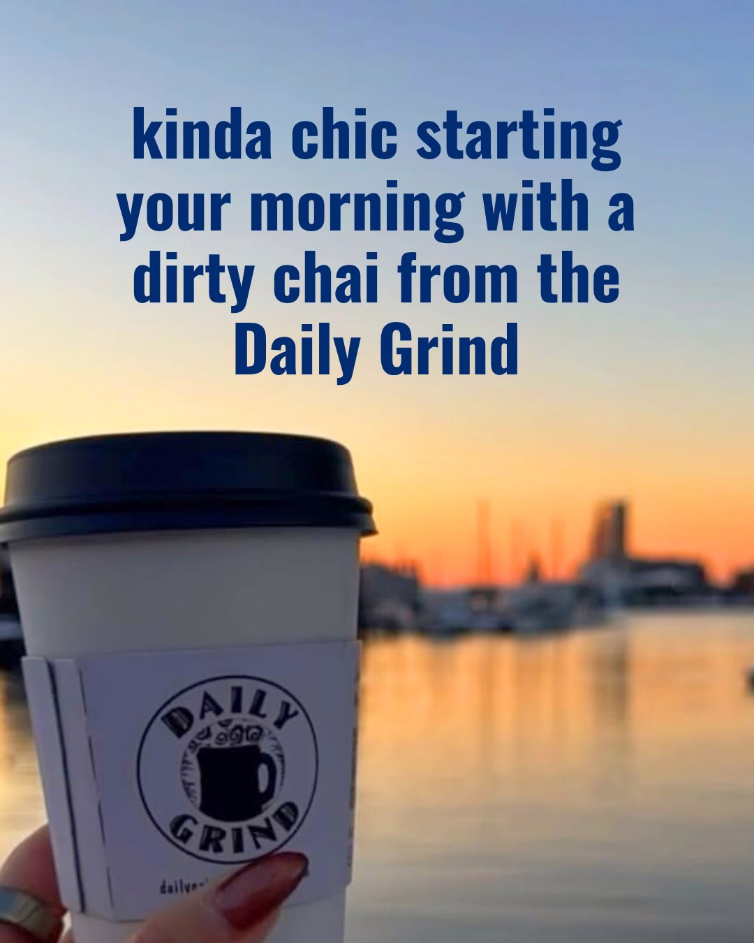 Coffee cup with the sunrise over water in the background. Text reads: kinda chic starting your morning with a dirty chai from the Daily Grind